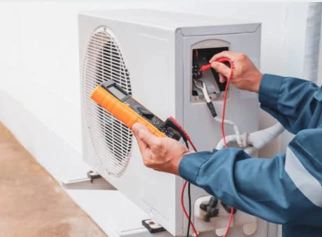 Technician testing electrical connections on an outdoor air conditioning unit