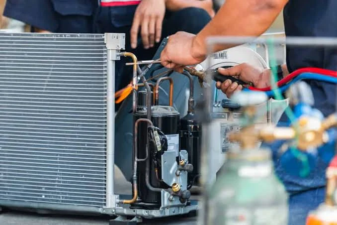 Close-up of technicians repairing HVAC tubing and internal components