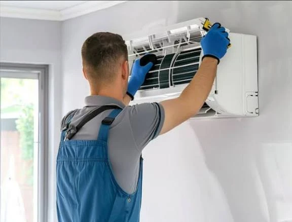 Technician removing a filter from a wall-mounted indoor air conditioner