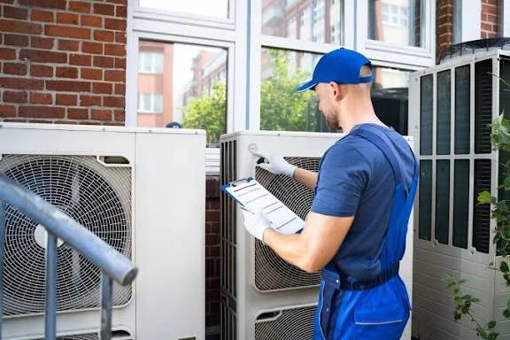 HVAC technician inspecting outdoor units and recording system details