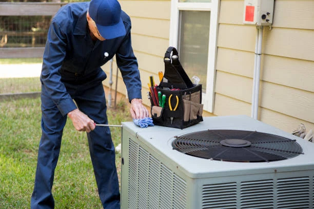 Technician servicing a residential outdoor condenser beside a home